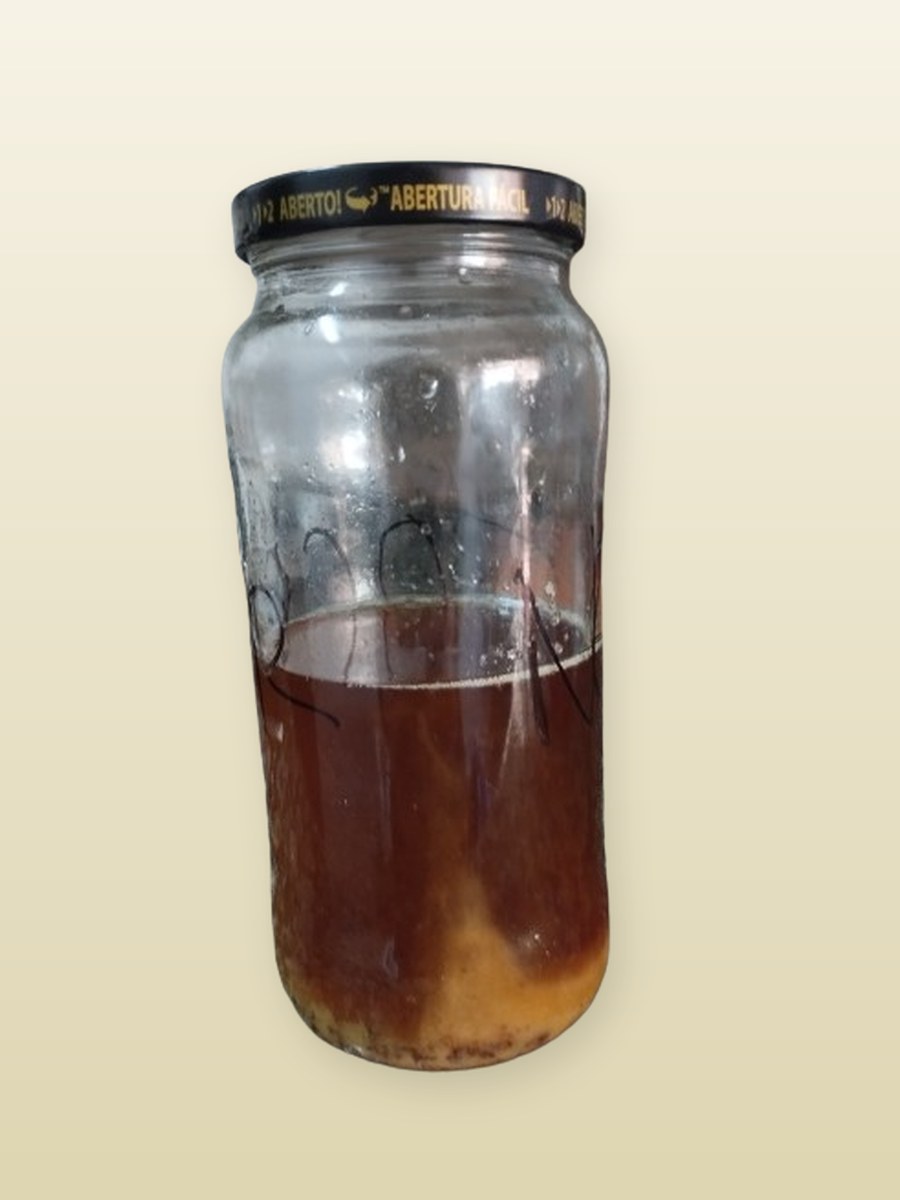 Bote de cristal con el aceite de oliva usado sin filtrar, con los restos de fritura posados en el fondo