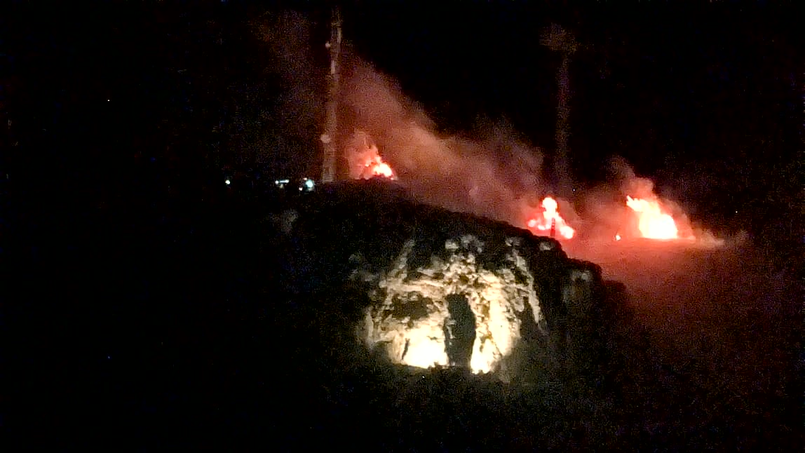 Los montones ardiendo en lo alto de Peña Blanca la noche del 23 de agosto, con la Piedra del Mediodía iluminada debajo, en Carcelén (Albacete).