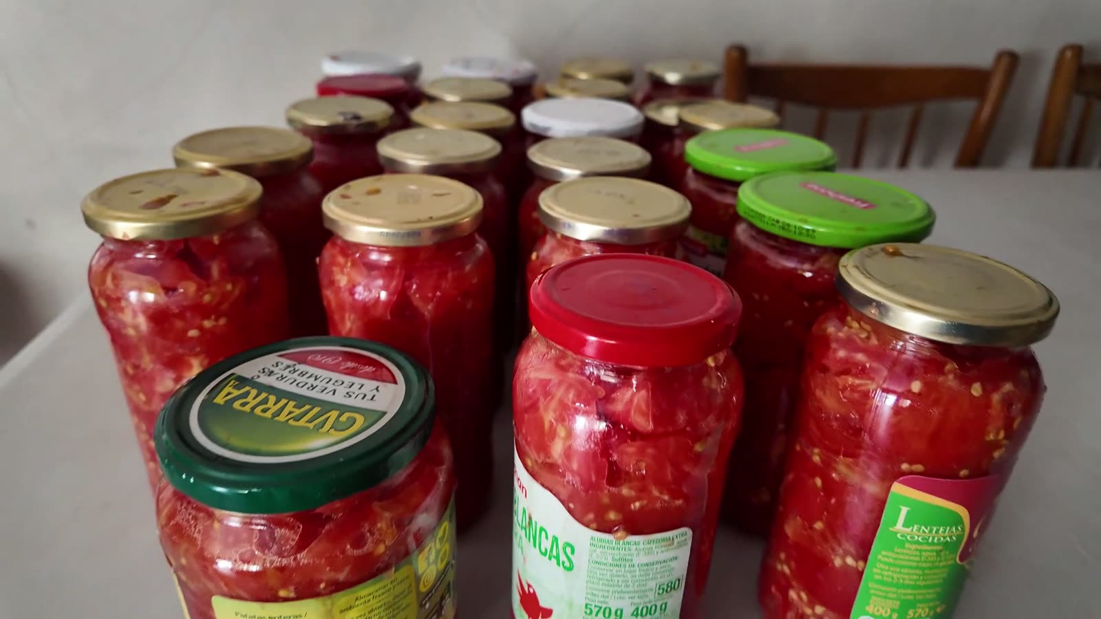 Fila de botes de tomate ya cerrados, reciclados de garbanzos y lentejas, con sus etiquetas y tapas originales