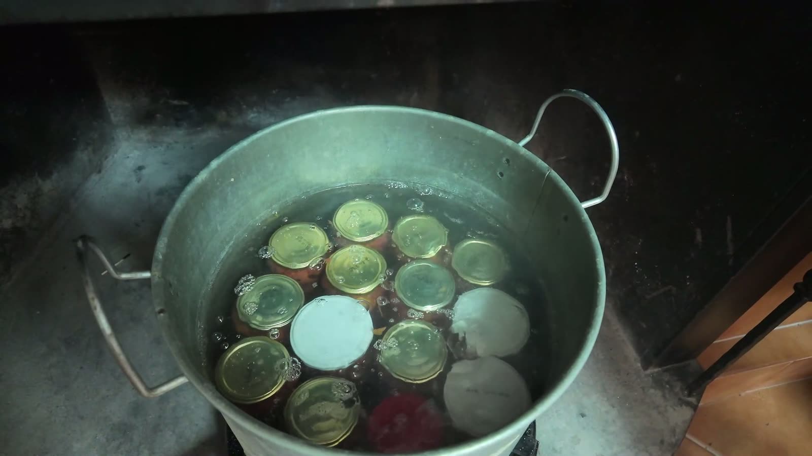 Olla al fuego con el agua hirviendo cubriendo los botes de tomate dos o tres dedos por encima de las tapas